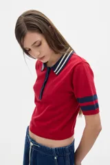 Remera polo corta color rojo con cuello y mangas con rayas azul marino y blanco.