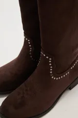 Botas texanas negras de caña media, confeccionadas en gamuza. Presentan un diseño de estilo western con detalles de tachas metálicas plateadas decorando el borde superior y el contorno del empeine. Tienen un taco bajo y punta ligeramente afilada.