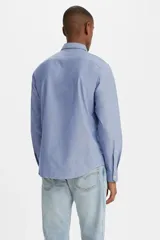 Camisa celeste de manga larga, corte clásico, con cuello abotonado, bolsillo en el pecho y logo de la marca en rojo.