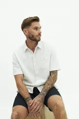 Camisa de manga corta color beige, con textura tipo crepé y cuello camisero.