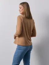 Blusa blanca de poliéster y elastano, con cuello a la base, escote en V y mangas tres cuartos. Presenta dos bolsillos frontales con cierre metálico dorado.