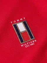 Chomba roja de piqué de algodón, corte regular, cuello clásico y tapeta de dos botones. Logo vertical de Tommy Hilfiger bordado en el pecho.
