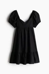 Vestido corto negro con escote corazón, mangas cortas abullonadas con elástico en hombros y puños, espalda fruncida y falda con vuelo.