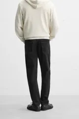 Pantalón de jean celeste de corte slim fit y tapered, con cinco bolsillos, efecto lavado y cierre frontal con cremallera y botón.