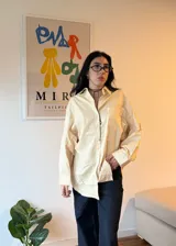 Camisa color crema a rayas verticales finas, de corte oversize y manga larga.