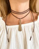 Choker de tira marrón con colgante metálico en forma de pirámide, largo del tiento de 140 cm.