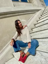 Sweater de punto calado color crema, con cuello, puños y ruedo en marrón con lurex. El cuello puede usarse de dos formas: mostrando un hombro o de forma clásica.