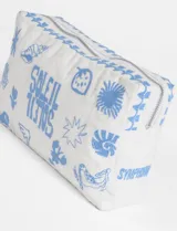 Estuche rectangular blanco de algodón con bordados en azul de motivos marinos y la palabra 'soleil'. Tiene cierre superior y borla decorativa en el cierre.