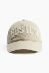 Gorra de sarga color beige con bordado en relieve de la palabra "Boston" y "Massachusetts".