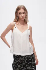 Musculosa blanca de bretel ancho con cuello en V y detalle de ojales metálicos en los tirantes. Corte al cuerpo.