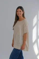 Blusa beige de lino con detalle de bordado floral y perforaciones en el lateral.