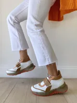 Zapatillas deportivas blancas con detalles en cuero color salmón y suela gruesa con detalles en naranja.