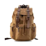 Mochila de tela canvas color verde oliva con tapa y detalles en símil cuero marrón. Cierre superior marinero, bolsillos internos, externos frontal, laterales y trasero con cierre. Asas rígidas, correas ajustables y espacio para laptop de 15".