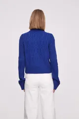 Sweater azul con cuello alto y diseño de trenzas.