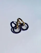 Par de aros colgantes con argollas doradas y dijes circulares de resina transparente con incrustaciones de strass de colores. El dije mide aproximadamente 1.5cm de diámetro.