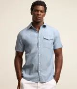 Camisa de hombre de manga corta en lino color blanco, con cuello clásico, botonadura frontal y bolsillo de parche en el pecho. Corte recto.