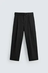 Pantalón negro de corte amplio con cinturón de tela con hebilla metálica. Presenta pliegues frontales, bolsillos laterales y traseros. Cierre frontal con cremallera y botón.