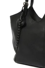 Cartera negra tipo shopper con textura símil cuero, doble asa de hombro y llavero colgante con forma de corazón.