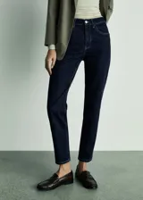 Pantalón de jean azul oscuro, tiro alto, corte mom fit, con cinco bolsillos y cierre de cremallera y botón.
