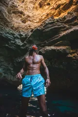 Short de baño celeste con estampado de hojas y flores en tonos naranja, verde y gris. Tiene elástico en la cintura, tres bolsillos y logo de la marca en la parte trasera.