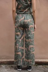 Pantalón de lino y algodón color verde con estampado de leopardos y estrellas blancas, corte palazzo con elástico en la cintura y bolsillos laterales.