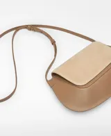 Bandolera pequeña de piel bovina en tonos camel y beige. El cuerpo principal es de piel lisa color camel con forma redondeada, y la solapa frontal es de serraje (gamuza) color beige claro. Posee un asa larga regulable y un tarjetero en el interior y exterior.
