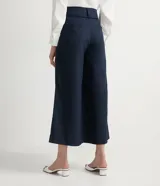 Pantalón pantacourt azul marino de lino y algodón, con cintura alta, pliegues delanteros, bolsillos laterales y cierre frontal con cremallera y botones.