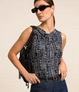 Blusa sin mangas de microfibra leve, color azul marino con estampado geométrico en blanco y escote drapeado.