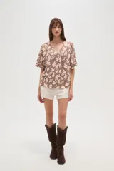 Blusa marrón con estampado de hojas color crema, cuello en V y mangas cortas. Corte holgado.