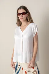 Blusa blanca de seda con escote en V y tabla en el frente. Manga corta.