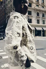 Blazer de tejido con estructura color crudo, con estampado de flores bordadas en negro. Tiene cuello solapa, manga larga y cierre frontal con botones negros.