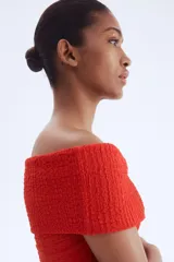 Top rojo con textura, corte ajustado y hombros descubiertos.