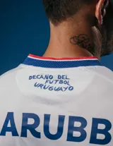 Camiseta oficial de fútbol color blanca, con el logo del club Nacional y detalles en azul y rojo.