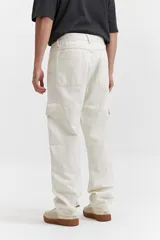 Pantalón cargo color beige, de corte recto, con bolsillos laterales y traseros. Se ajusta a la cintura con cinturón de cuero marrón.