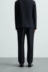 Pantalón de vestir azul marino, de corte recto, con bolsillos laterales y traseros. Se ajusta a la cintura con cinturón de cuero marrón.