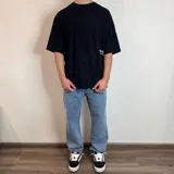 Remera negra con estampado de hongos y texto en la espalda, corte oversize.