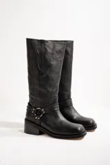 Botas de cuero negras con caña alta, taco cuadrado y detalle de arnés con hebillas metálicas.