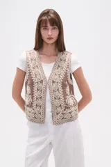 Chaleco sin mangas color marrón topo, con escote en V y bordados intrincados en color crema/blanco que cubren toda la prenda.