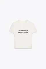 Camiseta color crema de algodón con efecto lavado, corte regular, cuello redondo, manga corta y texto marrón estampado en el frente con la frase 'Sun-Kissed in Maldives'.