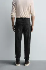 Pantalón de jean azul oscuro con efecto lavado y roturas en las rodillas, de corte ajustado al cuerpo desde la cintura hasta el tobillo.