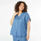 Blusa celeste de tela liviana, con cuello mao, manga corta remangable y corte holgado.