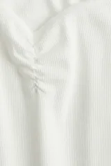 Top blanco de algodón en punto acanalado de raya fina. Modelo de manga corta con escote bote extraamplio y costura fruncida en el busto.