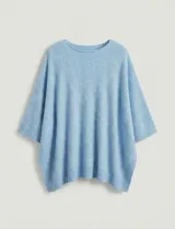 Poncho tejido de punto grueso, color mostaza/mostaza oscuro, con cuello redondo y caída amplia.