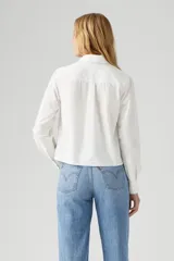 Camisa blanca de manga larga con bordado floral en el frente y detalle de puntilla en los puños.