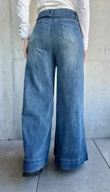 Pantalón de jean azul de corte pata de elefante, con bolsillos frontales tipo parche.