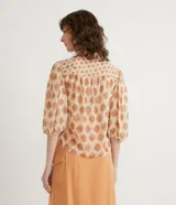Camisa de gasa color beige con estampado de lunares marrones, cuello mao, mangas 3/4 abullonadas y cierre frontal con botones.