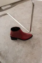Bota corta negra de cuero, con punta fina y taco cuadrado.