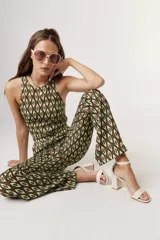 Top corto tipo crop top, sin mangas y con cuello halter. Presenta un estampado grande de flores en tonos verde claro, verde azulado y beige/crema.