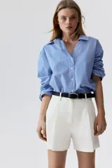Short color crudo de lino con tiro alto, pinzas delanteras, bolsillos laterales y cierre con botón y gancho ocultos.