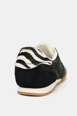 Zapatillas deportivas negras con detalle de estampado animal en la parte trasera, suela color caramelo y ajuste con cordones.